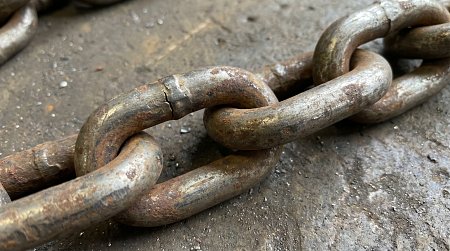 Zbliżenie na zużyte ogniwa łańcucha przemysłowego pokazujące oznaki korozji i mechanicznego zużycia